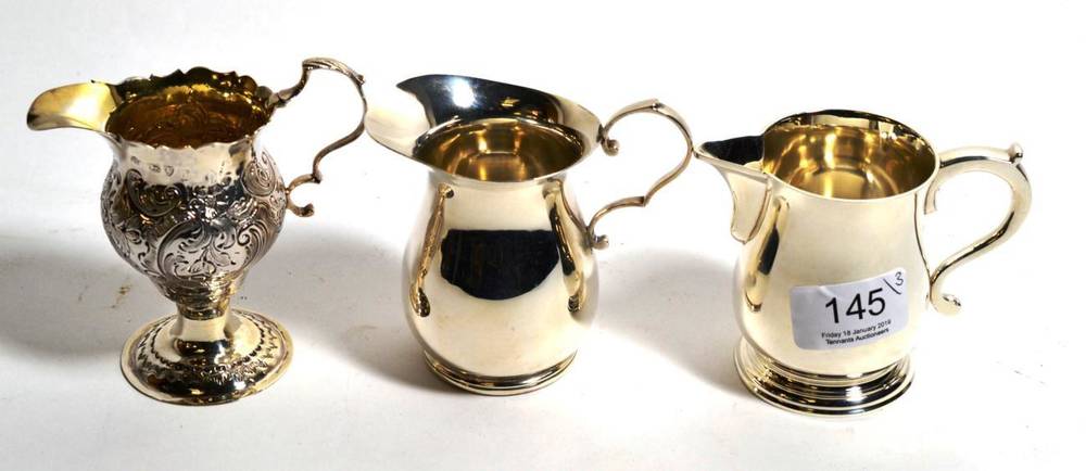 Lot 145 - Three silver cream jugs, comprising: a plain baluster example in the form of a beer jug,...