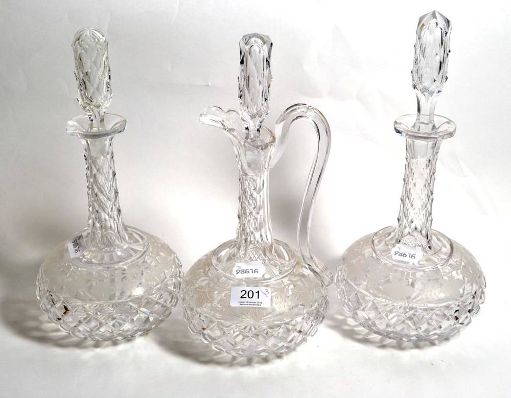Lot 201 - A pair of cut glass decanters etched with leaf and grape design, with matching claret jug