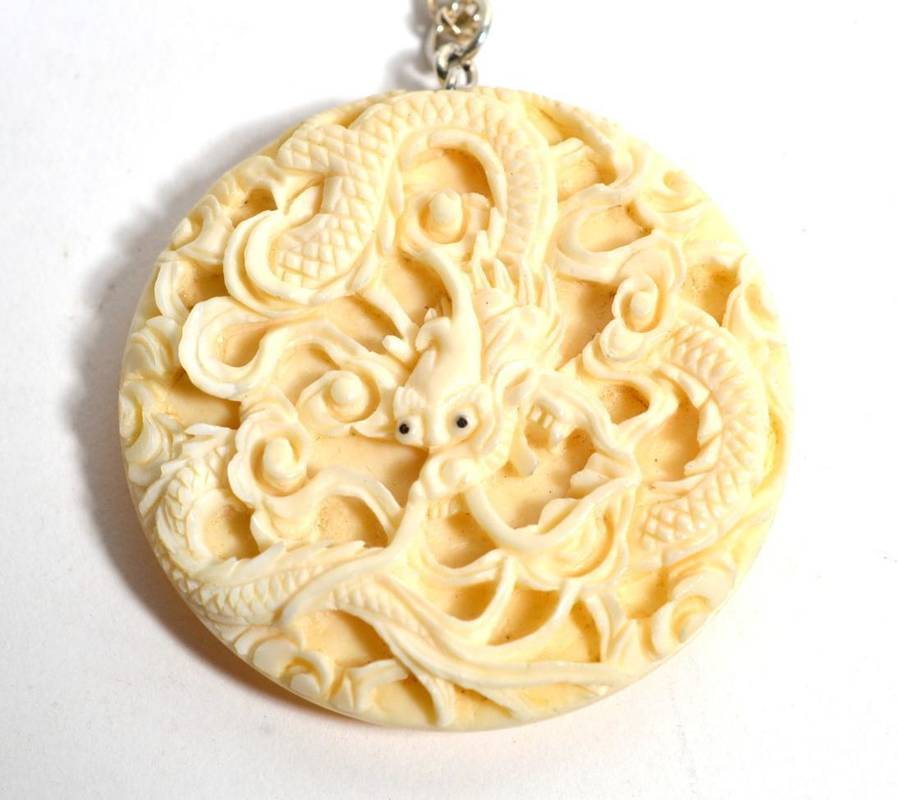 Lot 239 - A Chinese ivory pendant/button, depicting a dragon, with an attached silver chain