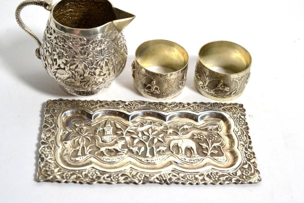 Lot 260 - An Indian Kutch white metal jug, heavily embossed, 8cm height; with three other similar items (4)