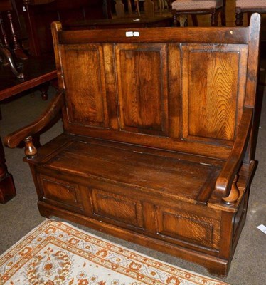 Lot 1239 - A reproduction joined oak box settle with a fielded panel back support, 116cm wide