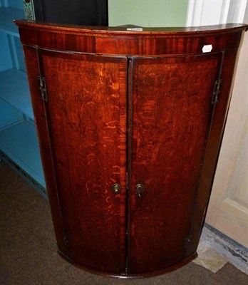 Lot 1258 - A George III oak and mahogany crossbanded bow fronted hanging corner cupboard