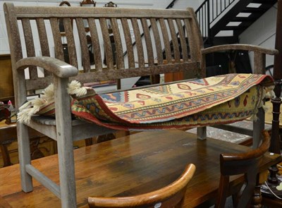 Lot 1118 - A slatted wooden garden bench together with an Anatolian rug (132cm by 90cm) (2)