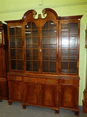 Lot 1178 - A reproduction breakfront bookcase cabinet with parcel gilt broken swan neck pediment
