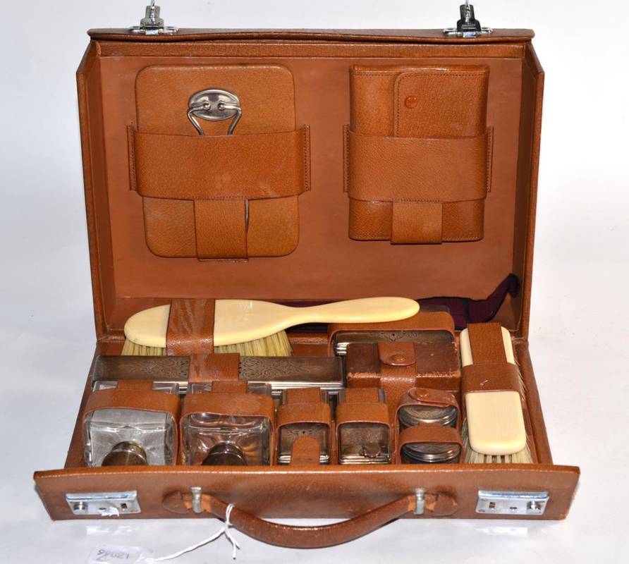 Lot 219 - A leather cased travelling dressing set, with silver topped bottles
