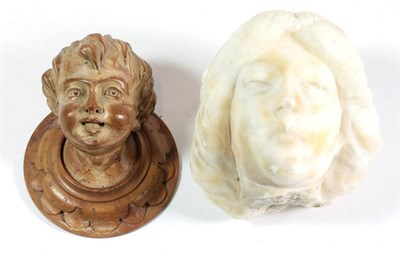 Lot 49 - A carved limewood head of a child, late 19th century, on a circular wall plaque, 13cm; and a carved