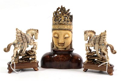 Lot 154 - An early 20th century ivory Buddha's head, on a wooden stand; and a pair of ivorine horse figures