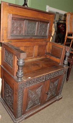 Lot 1353 - A Victorian carved oak cupboard, the hinged lid above two cupboard doors