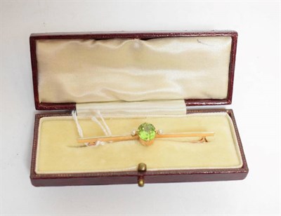 Lot 56 - An early twentieth century peridot and seed pearl brooch, an oval cut peridot in a claw...