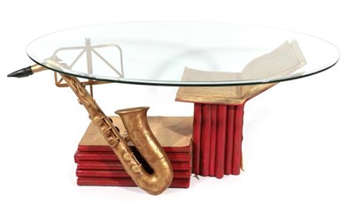 Lot 414 - A Glass Top Oval Coffee Table, modern, the bevelled glass top above a base in the form of music...