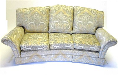 Lot 461 - A Three-Seater Sofa, modern, of curved form, upholstered in yellow and gold floral fabric, with six
