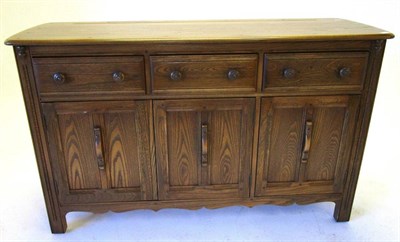 Lot 504 - An Ercol Originals Style Elm Sideboard, with three drawers above three cupboard doors, 143cm by...