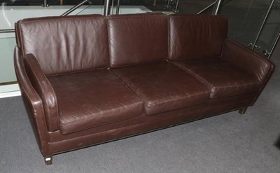 Lot 541 - A Danish Design Three-Seater Sofa, upholstered in brown leather, with padded back support and arms