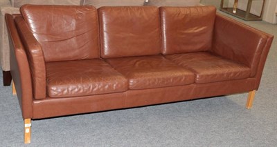 Lot 543 - A 1970's Danish Design Three-Seater Sofa, upholstered in brown leather, with padded back...