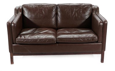 Lot 554 - A Danish Design Two-Seater Sofa, covered in brown leather, with padded back support and arms,...