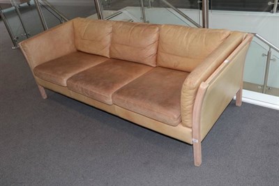 Lot 560 - A 1970's Danish Stouby Three-Seater Sofa, covered in light tan leather, with padded back...