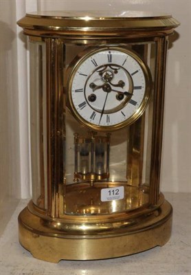 Lot 112 - An oval shaped brass four glass mantel clock, circa 1890, bevelled glass panels, 4-1/2-inch...
