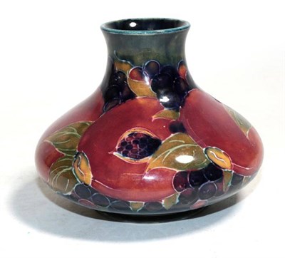 Lot 146 - William Moorcroft (1872-1945): A pomegranate pattern squat vase, on a blue ground, green...