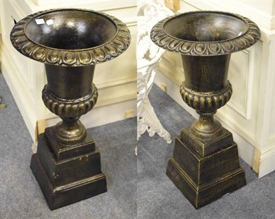 Lot 1078 - Pair of patinated metal urns on plinth bases in the classical taste