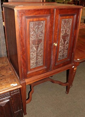 Lot 1315 - An early 20th century carved mahogany double door cabinet on stand