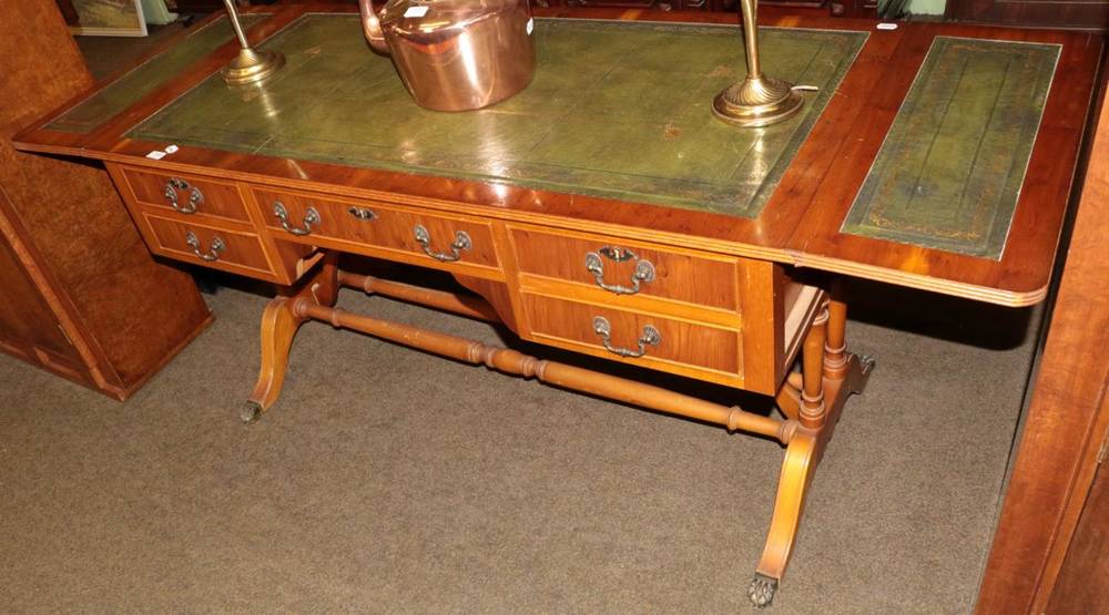 Lot 1385 - A reproduction yew wood drop leaf writing table in the Regency style