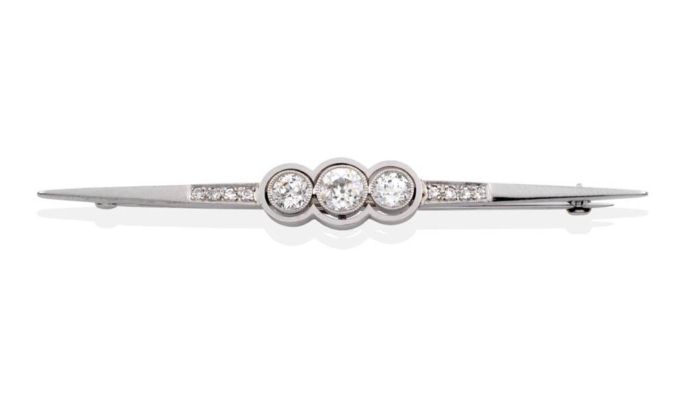 Lot 97 - An Art Deco Diamond Brooch, three grain set graduated old cut diamonds, within a circular halo...