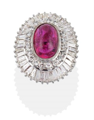 Lot 128 - A Ruby and Diamond Cluster Ring, an oval cabochon ruby in a rubbed over setting, within a...