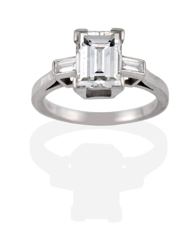 Lot 139 - ^ A Baguette Cut Diamond Solitaire Ring, in a claw setting, to baguette cut diamond set...