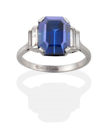 Lot 162 - ^ A Sapphire and Diamond Ring, an octagonal cut sapphire in a claw setting, to stepped baguette cut