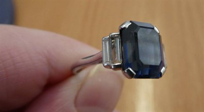 Lot 162 - ^ A Sapphire and Diamond Ring, an octagonal cut sapphire in a claw setting, to stepped baguette cut
