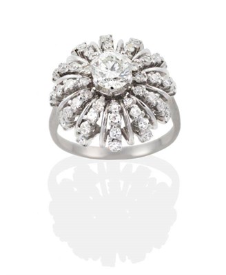 Lot 181 - A Diamond Cluster Starburst Ring, a round brilliant cut diamond within a frame of curved rows...