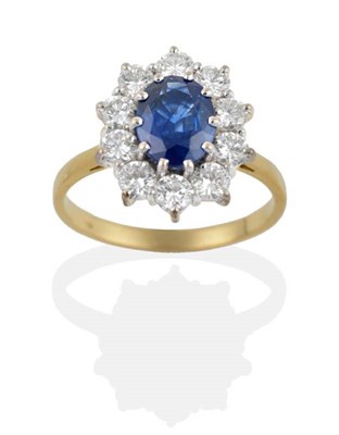 Lot 186 - An 18 Carat Gold Sapphire and Diamond Cluster Ring, the oval mixed cut sapphire within a border...