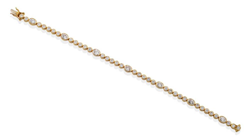 Lot 203 - ^ An 18 Carat Gold Diamond Line Bracelet, groups of round brilliant cut diamonds in rubbed over...
