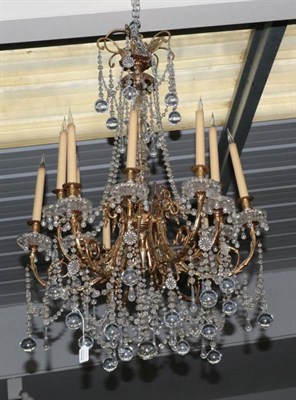 Lot 601 - ~ A Gilt Metal and Cut Glass Twelve-Light Chandelier, the scroll branches with urn sconces and...