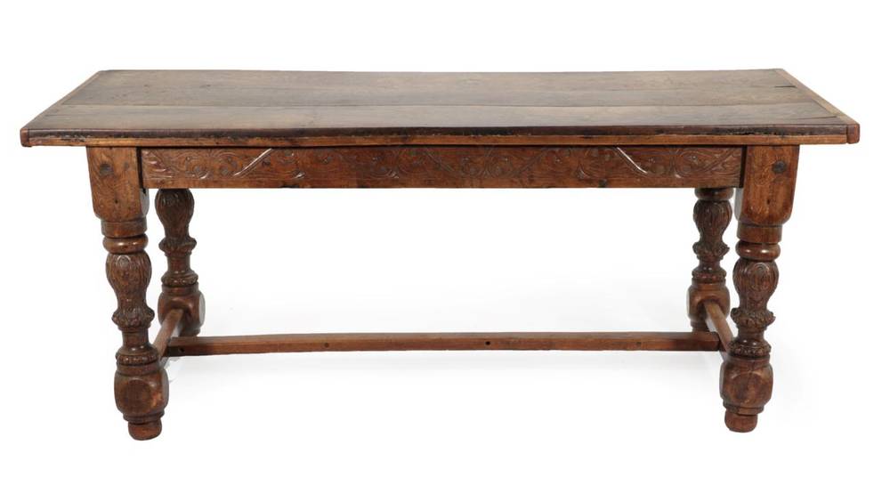 Lot 681 - A Carved Oak Dining Table, the three-plank top with cleated ends above a carved frieze of...