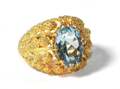 Lot 157 - An aquamarine ring, an oval cut aquamarine in a claw setting, within a broad tapering...