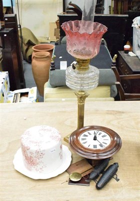 Lot 1116 - A brass oil lamp with cranberry glass shade; a small striking wall clock with pine cone...