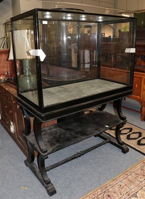 Lot 1222 - Late Victorian ebonised glazed display case on stand, the end section fitted a hinged door,...