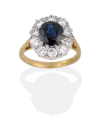Lot 2003 - An 18 Carat Gold Sapphire and Diamond Cluster Ring, the oval mixed cut sapphire within a border...