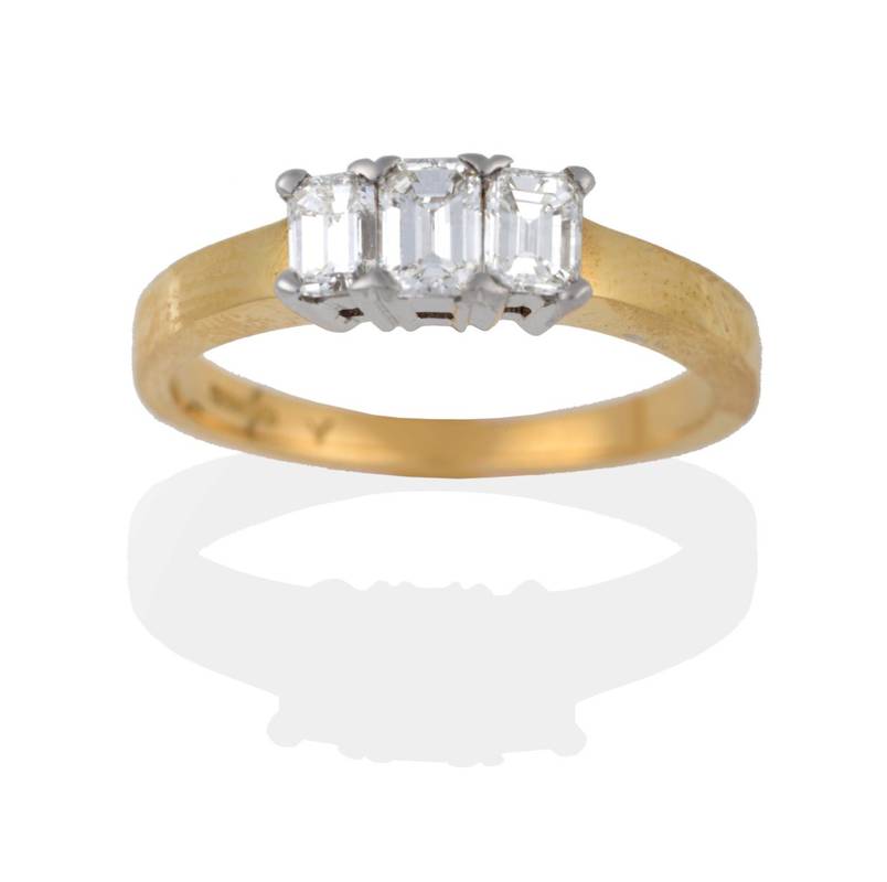 Lot 2016 - An 18 Carat Gold Diamond Three Stone Ring, the emerald-cut diamonds in white claws to a yellow...
