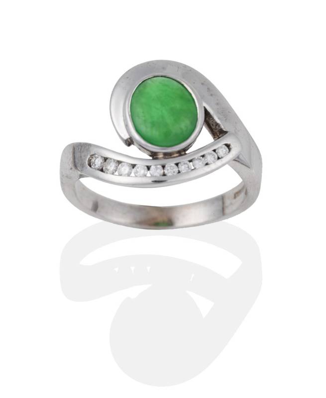 Lot 2023 - An 18 Carat White Gold Jade and Diamond Ring, an oval cabochon jade within a swirl frame with...