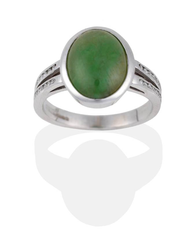 Lot 2025 - An 18 Carat White Gold Jade and Diamond Ring, the oval cabochon jade in a rubbed over setting...