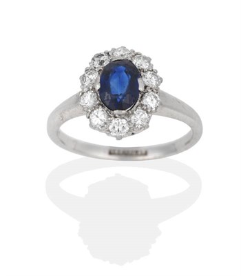 Lot 2035 - A Sapphire and Diamond Cluster Ring, the oval mixed cut sapphire within a border of round brilliant