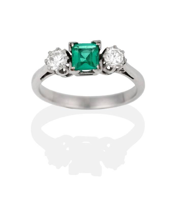 Lot 2042 - An Emerald and Diamond Three Stone Ring, the square step cut emerald between round brilliant...
