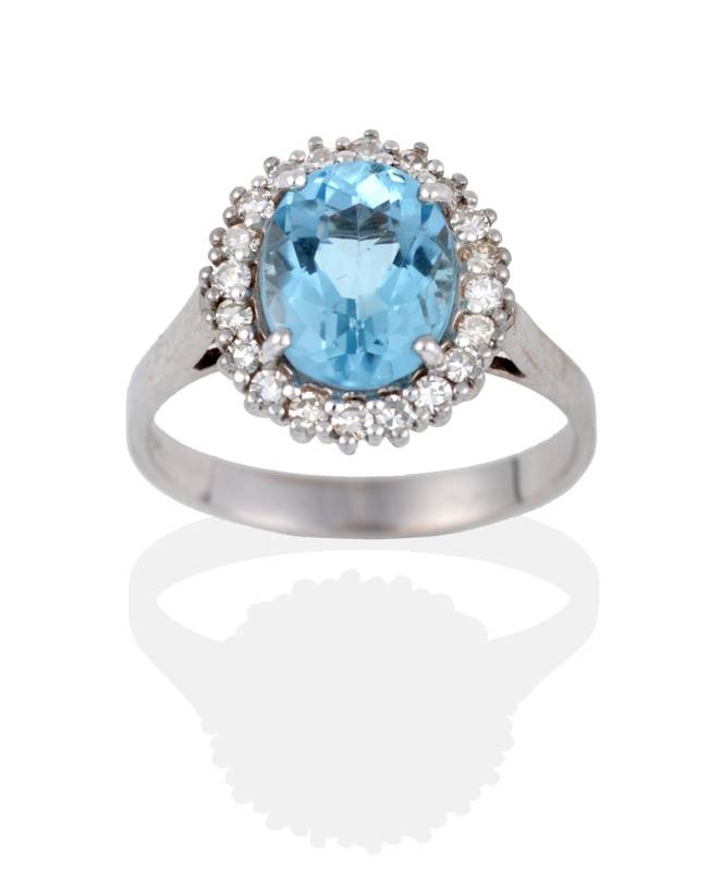 Lot 2084 - An Aquamarine and Diamond Cluster Ring, the oval cut aquamarine within a border of eight-cut...
