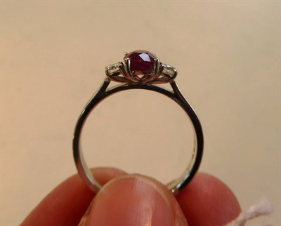 Lot 2095 - An 18 Carat White Gold Ruby and Diamond Three Stone Ring, the cushion shaped ruby between two round