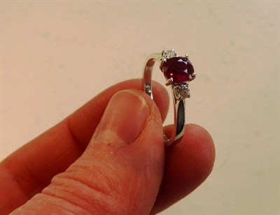 Lot 2095 - An 18 Carat White Gold Ruby and Diamond Three Stone Ring, the cushion shaped ruby between two round