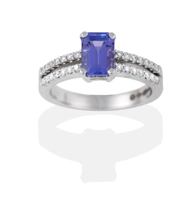 Lot 2100 - An 18 Carat White Gold Tanzanite and Diamond Ring, the emerald-cut tanzanite in a four claw setting