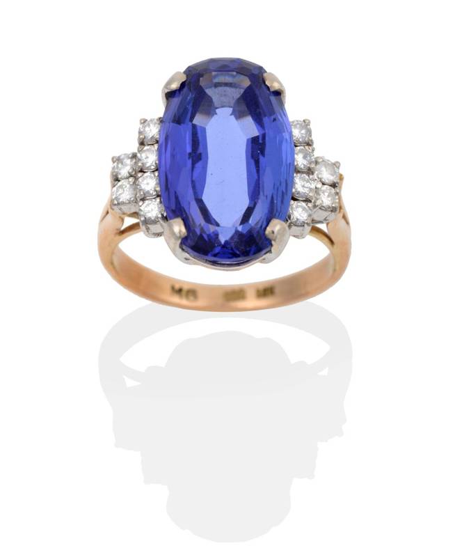 Lot 2123 - A Tanzanite and Diamond Ring, an oval cut tanzanite in a claw setting, to stepped diamond set...