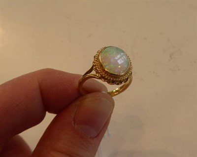 Lot 2127 - An 18 Carat Gold Opal Ring, an oval cabochon opal in a rubbed over setting, to a double stepped...
